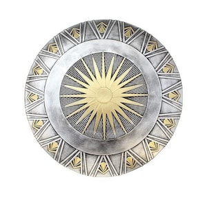May include: A circular shield in silver and gold. The centre has a gold sunburst design with black lines. The outer edge is silver with gold geometric accents. A classic superhero accessory, perfect for cosplay or display.