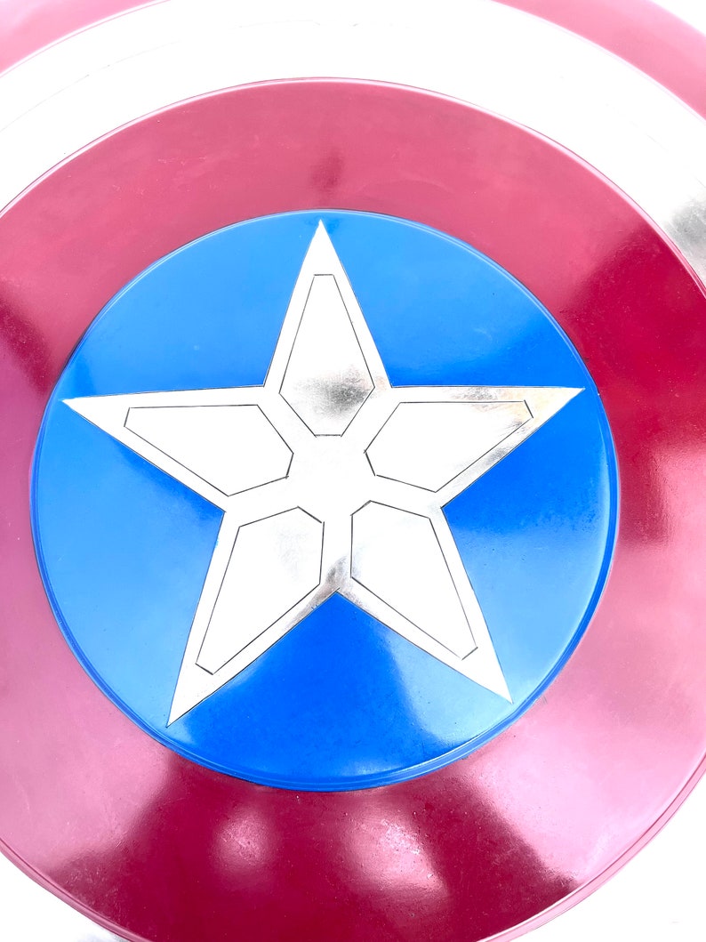 Pu&ograve; includere: Uno scudo di Capitan America rosso, bianco e blu con una stella argentata a cinque punte al centro.
