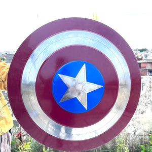 Pu&ograve; includere: Uno scudo di Capitan America rosso, bianco e blu con un bordo argentato. Lo scudo &egrave; rotondo e ha una stella a cinque punte al centro.