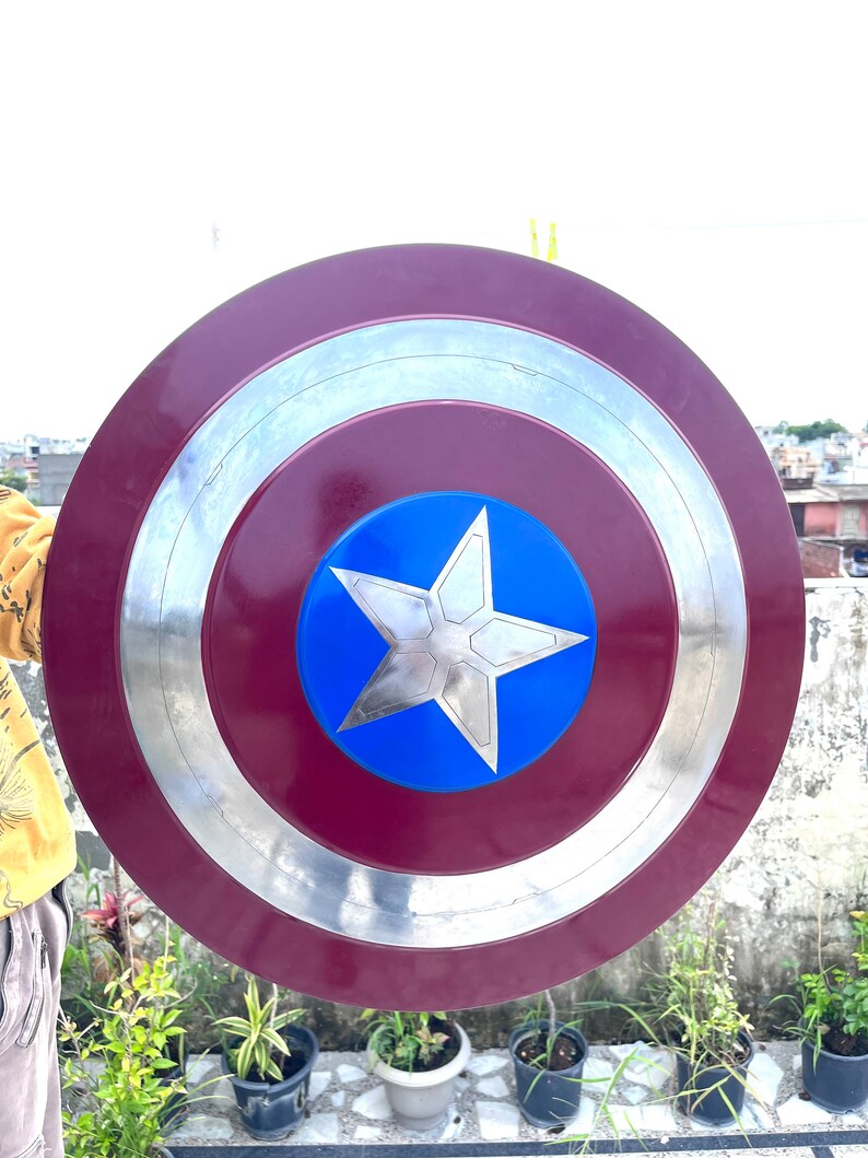 Pu&ograve; includere: Uno scudo di Capitan America rosso, bianco e blu con un bordo argentato. Lo scudo &egrave; rotondo e ha una stella a cinque punte al centro.