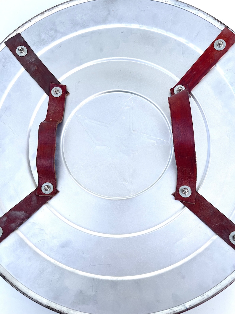 Pu&ograve; includere: Uno scudo di metallo argentato con una stella rossa al centro. Lo scudo ha due cinturini in pelle marrone con rivetti metallici fissati sul retro.