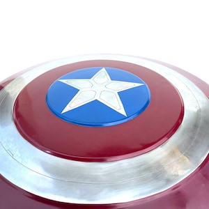 Pu&ograve; includere: Uno scudo di Capitan America rosso, bianco e blu con una stella argentata al centro. Lo scudo &egrave; fatto di metallo e ha una forma circolare.