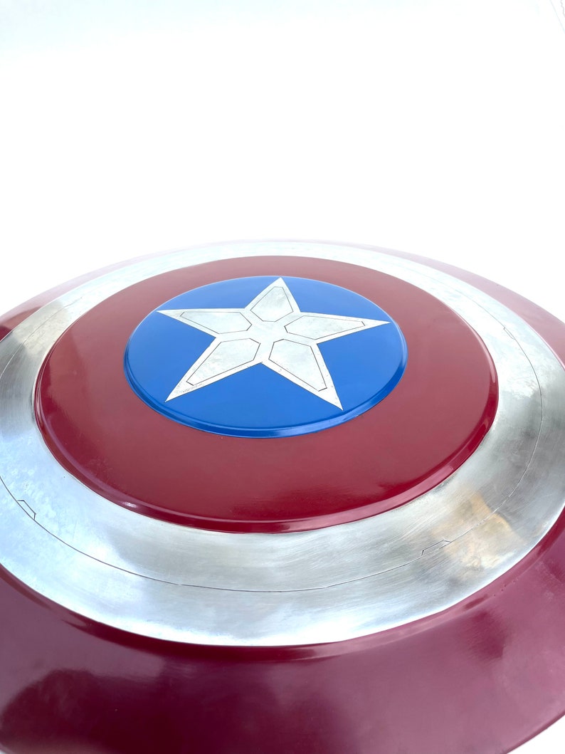 Pu&ograve; includere: Uno scudo di Capitan America rosso, bianco e blu con una stella argentata al centro. Lo scudo &egrave; fatto di metallo e ha una forma circolare.
