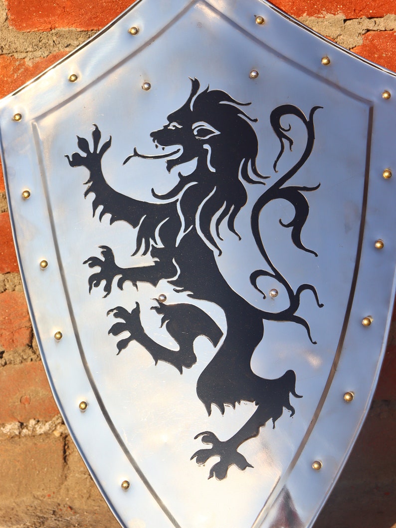 May include: A silver shield with a black lion design. The lion is standing on its hind legs with its tail curled up. The shield has a decorative border of gold studs.