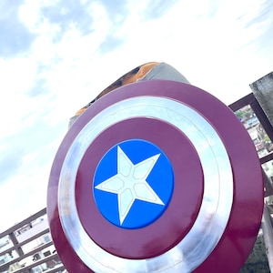 Pu&ograve; includere: Uno scudo di Capitan America rosso, bianco e blu con una stella a cinque punte al centro. Lo scudo &egrave; fatto di metallo e ha un bordo rialzato.