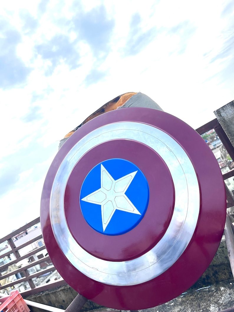 Pu&ograve; includere: Uno scudo di Capitan America rosso, bianco e blu con una stella a cinque punte al centro. Lo scudo &egrave; fatto di metallo e ha un bordo rialzato.