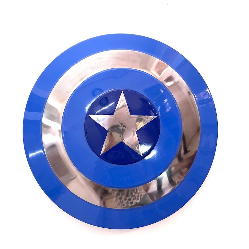 Puede incluir: Un escudo azul y plateado con una gran estrella plateada en el centro. El escudo tiene un dise&ntilde;o circular con un anillo exterior azul, un anillo central plateado y un centro azul con la estrella. Es un accesorio o art&iacute;culo de colecci&oacute;n.