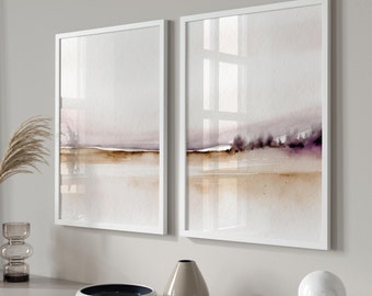May include: Two framed watercolor paintings with a muted purple and brown color scheme depicting a landscape with a horizon line and a reflection of the sky in the water. The paintings are hanging on a white wall above a light gray dresser with a vase, a bowl, and a sphere on top.