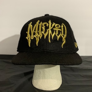May include: Black fitted baseball cap with a gold embroidered "Mickey" logo in a gothic font.