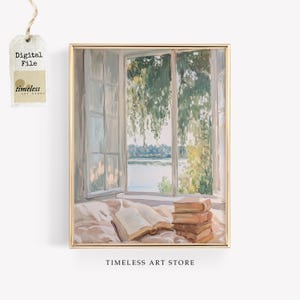 Puede incluir: Una pintura de una ventana con vista a un lago y árboles. Hay un libro y una pila de libros en una cama frente a la ventana. La pintura está en un marco dorado.
