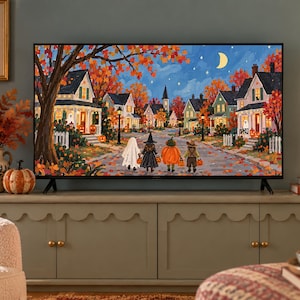 May include: A flat-screen television displaying a vibrant autumn neighborhood scene with children in Halloween costumes walking down a street. The screen shows houses, orange trees, a crescent moon, and a starry night sky, set within a decorated room.