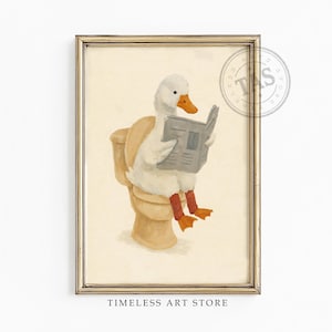 Peut inclure: Une impression d'art encadrée représentant un canard blanc au bec orange portant des jambières rouges, assis sur des toilettes beiges en lisant un journal gris. L'œuvre est dans un cadre doré et inclut le texte TIMELESS ART STORE.
