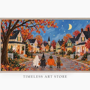 May include: A rectangular framed art print depicting a neighborhood street scene at night during autumn. Four figures in Halloween costumes walk down a leaf-covered road past houses with glowing windows, jack-o'-lanterns, and a crescent moon.