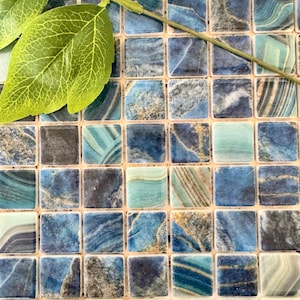 Może przedstawiać: Zbliżenie na arkusz mozaiki z niebieskich i zielonych płytek. Płytki są małe i kwadratowe, a mają marmurowy wzór. Płytki są ułożone w siatkę.