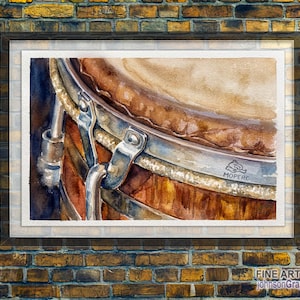 May include: Watercolour print of a drum, showing a close-up of the drumhead and metal hardware. The drum has a brown wooden body and silver metal accents. The print is framed and displayed against a brick wall.
