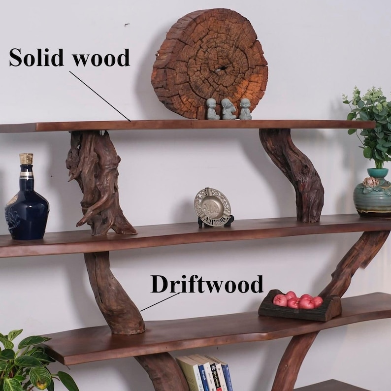 May include: A three-tiered shelf unit made of solid wood with driftwood branches as supports. The top shelf has a large, round, wooden slice with three small figurines on top. The middle shelf has a small, silver dish and a bottle of liquor. The bottom shelf has a small basket of red apples and a stack of books.