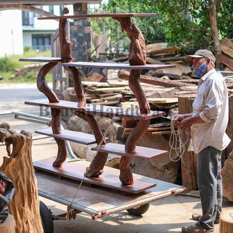 May include: A wooden shelf unit made from natural tree branches with four shelves. The shelves are stained a dark brown color. The unit is being loaded onto a flatbed trailer.