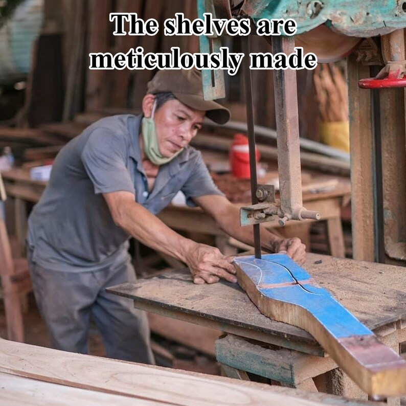 May include: A man uses a band saw to cut a piece of wood. The wood is marked with a blue line. The shelves are meticulously made.