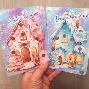 Op de afbeelding: Twee kleurrijke kaarten met het thema gingerbreadhuis met een roze en een blauwe gingerbreadhuis op elke kaart. De kaart met het roze gingerbreadhuis heeft de tekst "Lebkuchenfrau Leni..." en de kaart met het blauwe gingerbreadhuis heeft de tekst "Lebkuchenmann Leni..."