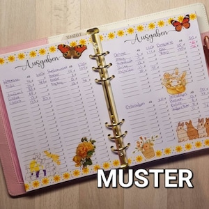 Puede incluir: Una agenda rosa y blanca con un diseño floral y una encuadernación dorada. La agenda tiene una sección para "Ausgaben" (alemán para "Gastos") e incluye una lista de artículos con precios. La agenda también tiene una sección para "Sonstiges" (alemán para "Miscelánea") e incluye una lista de artículos con precios.