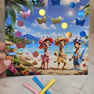 Könnte beinhalten: Eine rechteckige Karte mit drei Zeichentrick-Giraffen am Strand mit Palmen, einem Leuchtturm und einem Schild mit der Aufschrift TO THE BEACH. Die Karte ist mit verschiedenen bunten Glitzer-Schmetterlings- und Kreisaufklebern verziert. Drei Kunststoffstäbchen in Pink, Blau und Gelb liegen vor der Karte.