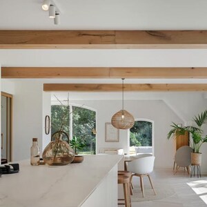 Puede incluir: Interior de cocina moderno y luminoso con encimera blanca y vitrocer&aacute;mica integrada. Vigas y estanter&iacute;as de madera a&ntilde;aden calidez. Se ven una batidora de pie y objetos decorativos. Grandes ventanales ofrecen vistas al exterior.
