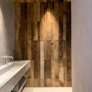 May include: A modern bathroom with a concrete sink and a wall made of reclaimed wood planks.