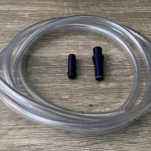 May include: A clear plastic tube coiled on a wooden surface. Two blue plastic pieces are next to the tube.