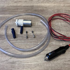 May include: A set of car accessories for inflating tires. The set includes a black electric air pump with a cigarette lighter plug, a clear plastic hose, two blue plastic connectors, and two silver fuses.