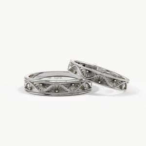 Pu&ograve; includere: Due anelli color argento caratterizzati da un motivo a onde ripetuto con sottili linee incise e piccoli accenti sferici. L'interno dell'anello pi&ugrave; largo &egrave; chiaramente stampigliato con il testo 14K, che indica la purezza del metallo dei gioielli.