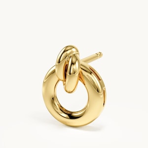 K&ouml;nnte beinhalten: Ein polierter Gold-Ohrstecker mit kreisf&ouml;rmigem Ringdesign und einem kleineren, glatten, abgerundeten Glied, das oben durchgezogen ist. Der Ohrstecker hat einen geraden Stift an der R&uuml;ckseite und eine durchgehend reflektierende Metalloberfl&auml;che.