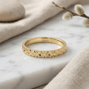 Może przedstawiać: Zestaw trzech ceramicznych kubków z nakrapianą, kremową glazurą. Każdy kubek ma inny ręcznie malowany wzór: niebiesko-zielony liść, żółty kwiat i czerwona jagoda. Kubki mają prosty, zaokrąglony kształt.