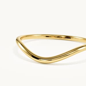 May include: A polished yellow gold ring featuring a smooth, continuous wave-like design. The band has a rounded profile and a high-shine reflective surface. The interior of the band is clearly stamped with the text 14K, indicating its metal purity.