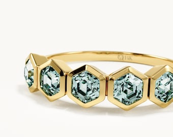 May include: A gold ring featuring five hexagonal settings arranged in a row. Each setting contains a pale mint green, faceted gemstone. The interior of the gold band is clearly stamped with the text 14K, indicating the metal purity.
