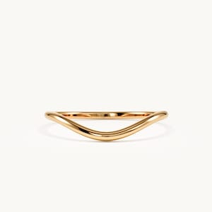 May include: A polished gold ring featuring a smooth, continuous band with a distinct V-shaped curve at the center. The metal has a reflective, high-shine finish that catches the light, creating a sleek and uniform appearance across the entire piece.