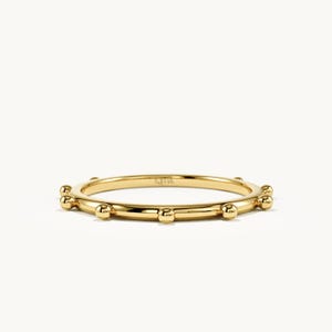 Könnte beinhalten: Ein Ring aus poliertem 14k Gelbgold mit einer dünnen, glatten Ringschiene, die rundherum mit gleichmäßig verteilten, kleinen kugelförmigen Perlen verziert ist. Auf der Innenseite ist der Text 14k zur Materialkennzeichnung eingeprägt.