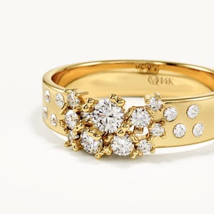 May include: A 14K yellow gold ring featuring a cluster of round brilliant-cut white diamonds set in a textured, organic arrangement across the front. The band is polished gold and includes the engraved text 14K on the inner surface.