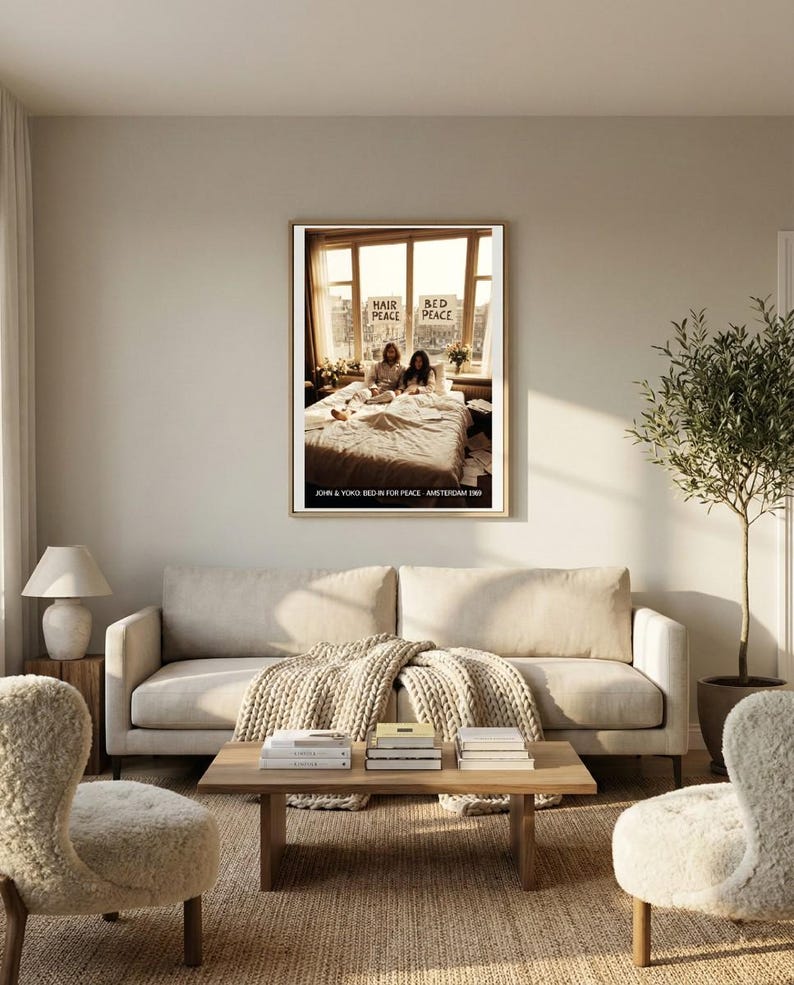 May include: A framed print featuring a photograph of John Lennon and Yoko Ono in bed, with the words "Hair Peace Bed Peace" visible. The print is displayed above a light-colored sofa in a living room setting.
