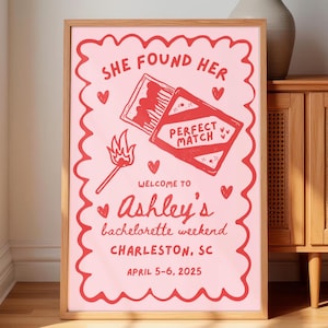 Könnte beinhalten: Gerahmtes rosa Poster mit rotem Text und Illustrationen. Der Text lautet „SHE FOUND HER PERFECT MATCH“ und „WELCOME TO Ashley's bachelorette weekend CHARLESTON, SC APRIL 5-6, 2025“. Die Illustration enthält eine Streichholzschachtel und ein brennendes Streichholz.