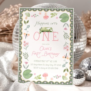 Può includere: Un invito di compleanno stravagante con un tema di rana e illustrazioni floreali. Il testo rosa dice "Hopping into ONE" per il primo compleanno di Olive. L'invito ha una tavolozza di colori verde e rosa.