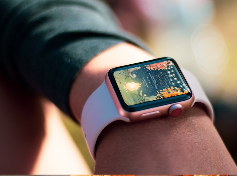 Pu&ograve; includere: Un Apple Watch bianco e oro rosa con un invito digitale per un fal&ograve; in giardino. L'invito presenta un'illustrazione ad acquerello di un fal&ograve; con foglie autunnali e luci a catena.