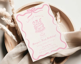 May include: A pink and white birthday invitation with the text "Girls just wanna be ONE". The invitation features a cake illustration and event details. The invitation is placed on a wooden tray with decorative elements.