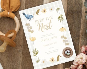 May include: A white and light blue baby shower invitation with a gingham pattern. The invitation features a bird, a nest with eggs, and flowers. The text on the invitation reads "Prep the Nest" and includes the date, time, and location of the shower.