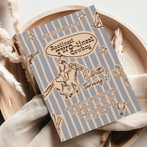 May include: A cowboy-themed birthday invitation with a light blue and tan striped background. The text reads "Rootinest Two-tinest Cowboy" and "Elliott's turning 2!" with illustrations of a cowboy on a horse, a gun, boots, stars, a cactus, and a bull's skull.