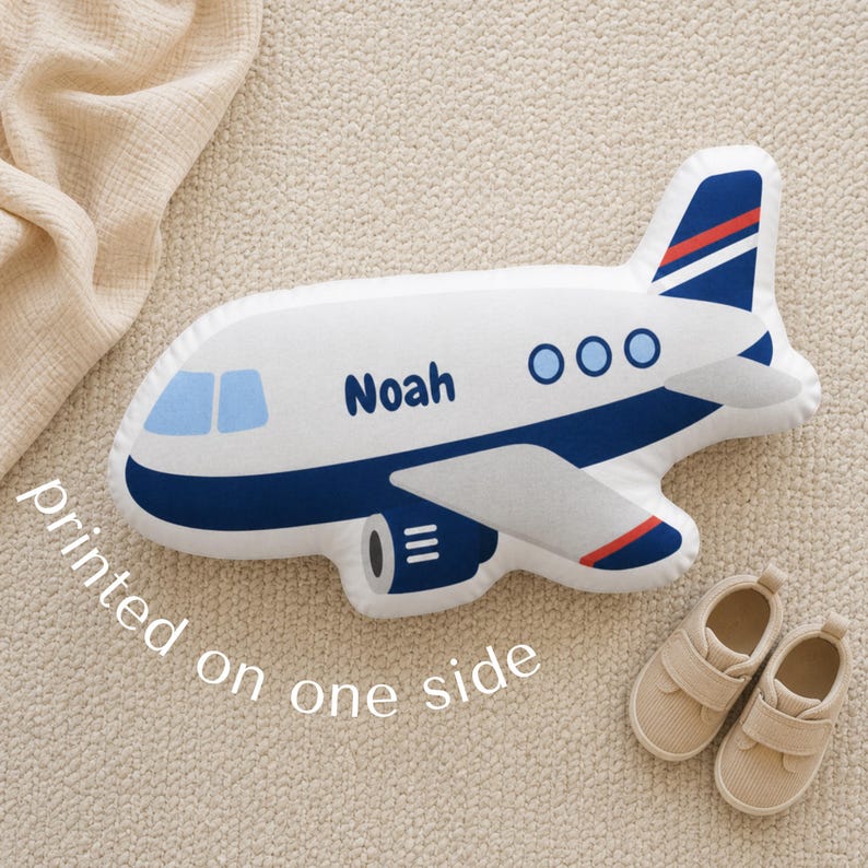 Custom airplane shaped pillow for kids personalized with the name Noah, styled in a soft neutral nursery with modern aviation themed decor, plush airplane cushion for toddler boy bedroom styling, transportation nursery inspiration, pilot baby shower gift ideas, travel themed kids room decoration, cozy personalized plush pillow for reading corners, nursery chairs, beds, and playroom seating areas