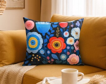 May include: Square decorative pillow with a floral pattern. The pillow features a dark blue background with colorful flowers in shades of red, blue, yellow, and pink. The pillow is placed on a yellow sofa.