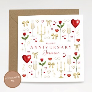 Può includere: Un biglietto di anniversario bianco con una busta marrone. La carta presenta cuori rossi, rose, calici di champagne e fiocchi d'oro. Le parole "Happy Anniversary Jasmine" sono scritte in rosso.