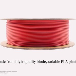 May include: A spool of bright red PLA filament for 3D printing. The filament is wound around a cardboard spool. The text "Made from high-quality biodegradable PLA plastic" is below the spool.