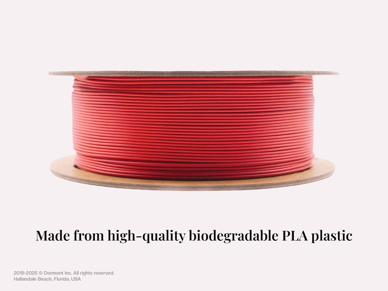May include: A spool of bright red PLA filament for 3D printing. The filament is wound around a cardboard spool. The text "Made from high-quality biodegradable PLA plastic" is below the spool.