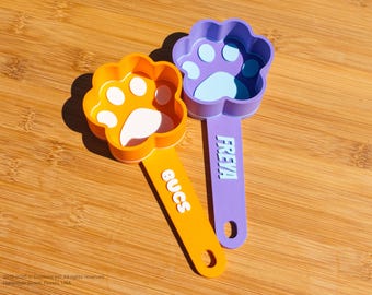 May include: Two orange and purple paw-shaped scoops with the words "BUGS" and "FREYA" printed on the handles.